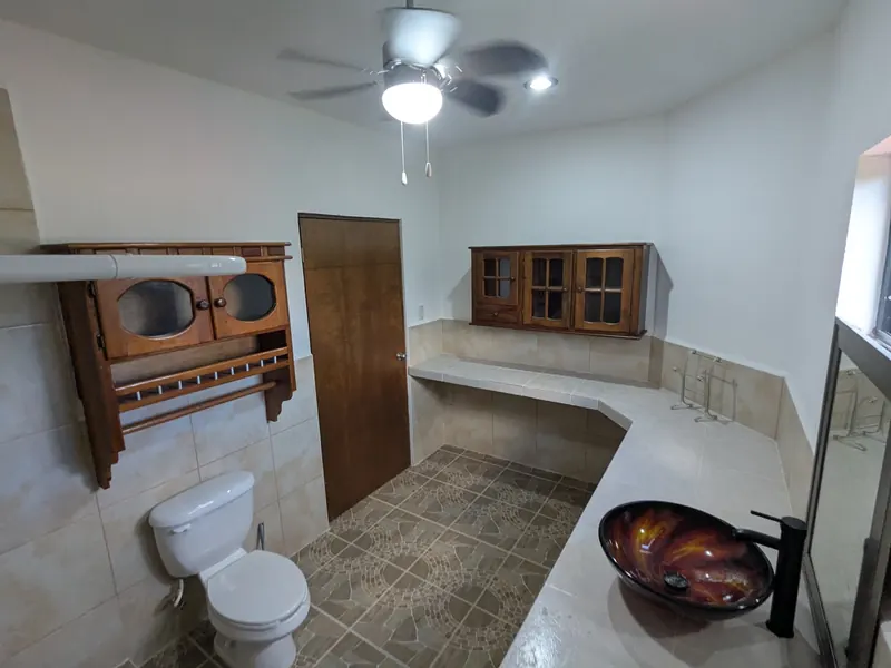 Baño de planta alta con cubierta de azulejo y lavabo de vidrio artístico.