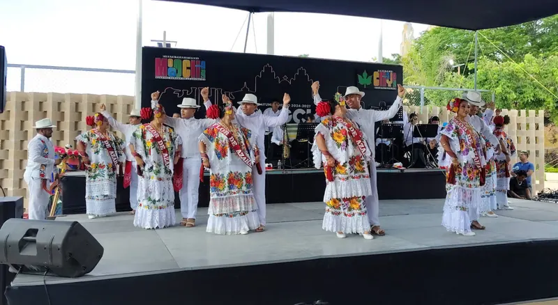 Bailarines de jarana con hipiles y guayaberas sobre el escenario de la fiesta.