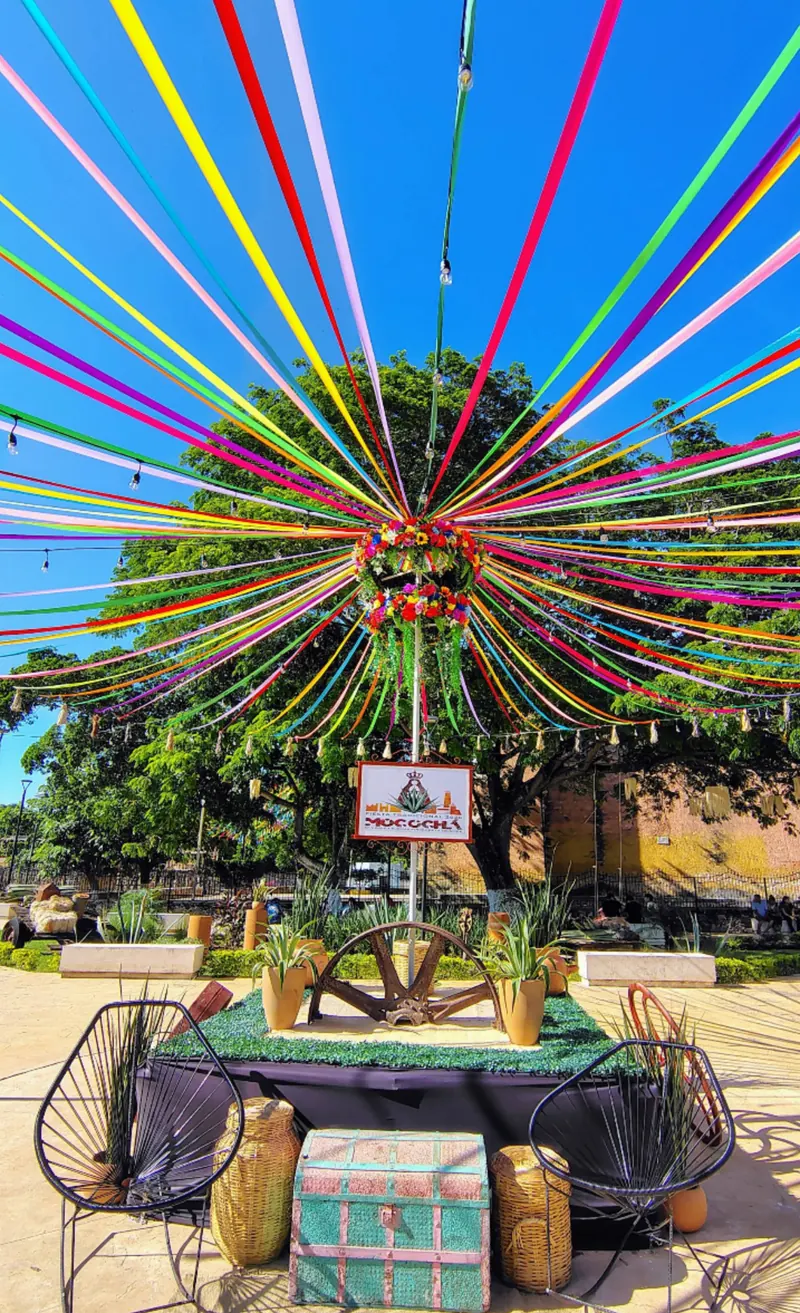 Listones de colores sobre la plaza, con la corona de la fiesta y el letrero del pueblo.