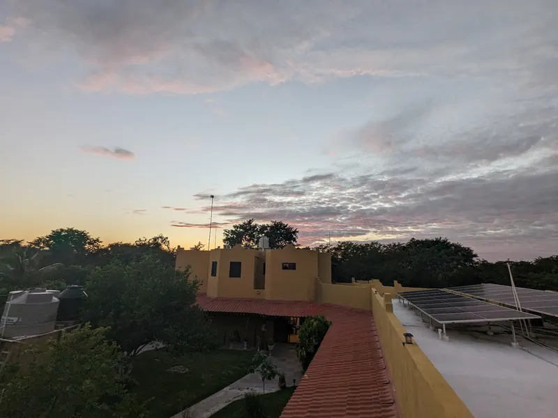 Atardecer desde la azotea, sobre la casa y los paneles solares.
